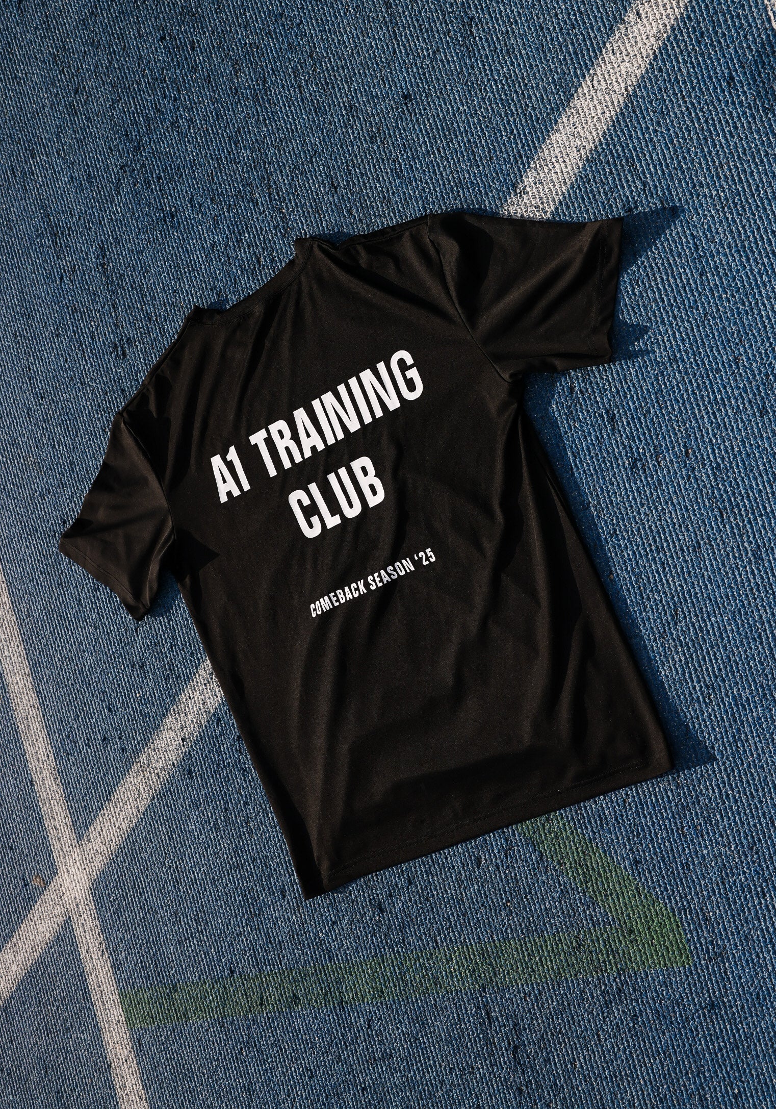 Black t-shirt with 'AI Training Club' text on a blue textured surface